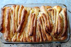 a glass baking dish filled with french toasted pastries on top of a marble counter