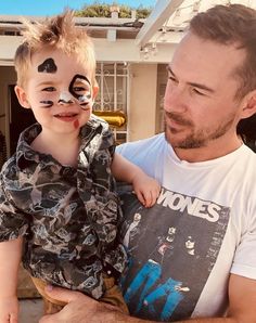 a man holding a child with face paint on it