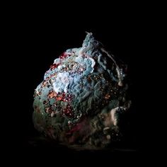 a rock covered in lots of different types of rocks and gravel on a black background