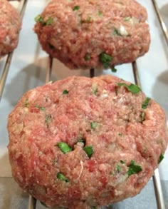 four hamburger patties sitting on top of a metal rack