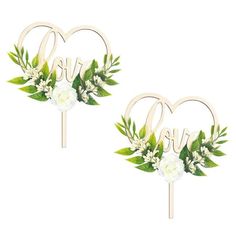 two wedding cake toppers in the shape of hearts with flowers and leaves on them