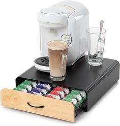 a coffee maker and cups are sitting on a tray with the lid open to hold drinks