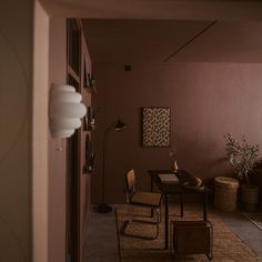 a room with a table, chairs and plants in it is seen from the hallway