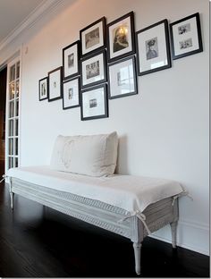 a white bench sitting in front of a wall with pictures on it's sides