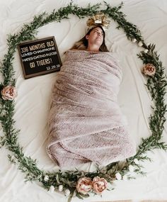 a woman wrapped in a blanket laying on top of a bed next to a sign