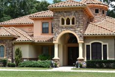 a large house with two story windows and arched arches on the roof, surrounded by greenery