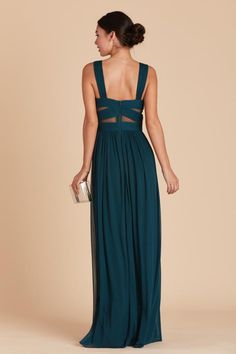 a woman in a long green dress is looking back at the camera and she has her hand on her hip