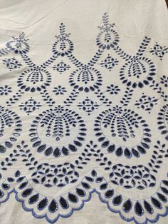 a white table cloth with blue and black designs on the edges, sitting on top of a wooden table