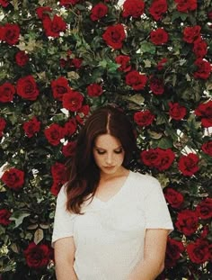 a woman standing in front of red roses