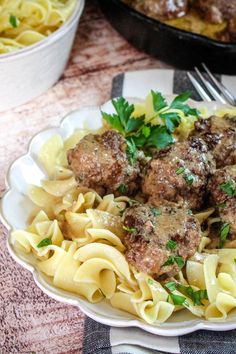 pasta with meatballs and parsley in a white bowl on a checkered tablecloth