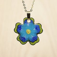 a blue and green flower is hanging from a chain