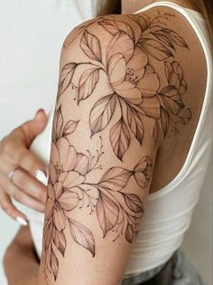 a woman's arm with flowers and leaves tattooed on the back of her shoulder