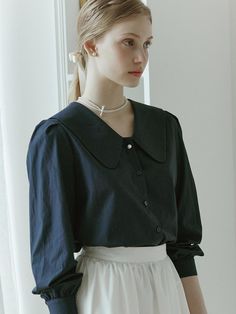 This is NONLOCAL’s blouse exudes a clean look. It's made from a soft-touch blend of rayon and cotton, offering a luxurious feel with just the right amount of flow. The subtle shirring on the shoulders and cuffs, along with the classic flat collar line, stand out. The pearl button accents on the sleeves add a feminine touch.- Ideal for daily wear- Can be paired with different bottoms to create various looks- Features back pleat detailing and brand logo symbol embroidery on the side for added flair Classic Solid Tops With Peter Pan Collar, Classic Blouse With Peter Pan Collar For Fall, Classic Workwear Blouse With Peter Pan Collar, Classic Peter Pan Collar Top For Fall, Classic Tops With Peter Pan Collar For Office, Classic Office Top With Peter Pan Collar, Elegant Solid Color Top With Peter Pan Collar, Elegant Solid Color Tops With Peter Pan Collar, Elegant Solid Tops With Peter Pan Collar