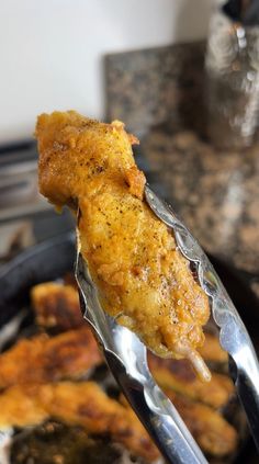 a piece of chicken is being held up by a fork with some food on it