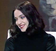 a woman sitting in a chair smiling for the camera