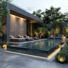 an outdoor swimming pool surrounded by greenery and lights at night with couches on the side