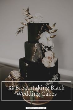 a black and gold wedding cake with white flowers on the top, sitting on a table