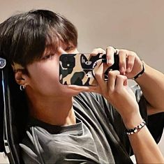 a boy taking a photo with his cell phone while wearing headphones and sitting in a chair