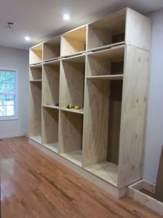 an empty room with wooden shelves in the middle and hard wood flooring on the other side