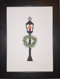 a cross stitch picture with a lamp post