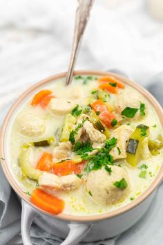 a bowl filled with chicken and dumpling soup on top of a white table cloth