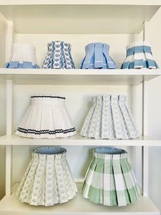 several lamps are lined up on shelves in a room that is white and has blue trim