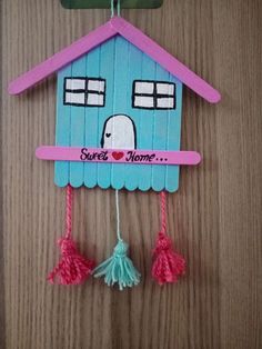 a paper house hanging on a wall with tassels