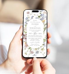 a woman is holding up her phone to show the wedding card on it's screen