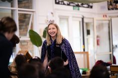 a woman wearing a tiara standing in front of a group of people with headphones on