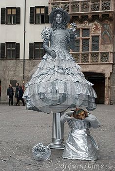 a woman in a silver dress standing next to a statue