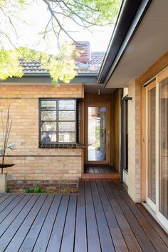 an empty wooden deck in front of a brick house with large sliding glass doors on both sides