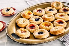 several small pastries are on a platter next to two plates with jams