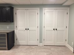 two white closet doors in a room with black cabinets and an oven on the floor