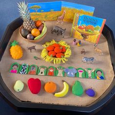 an assortment of fruits and vegetables on a tray with a children's book in the background