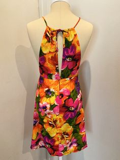 "Original to the 60s. Fab MINI Dress!! Bright bold floral pattern. Front cut out detail at chest, toe back neck, hidden back zipper and button closure. Mannequin is a US Size 4, and the dress fits her like a glove, for your sizing reference. Measurements laying flat - The high waist is empire style and hits just below the bust. Measures 13\" laying flat. Total length of dress is 31\" (mini dress) The halter style neck ties at back Tiki Time!" Backless Floral Mini Dress For Garden Party, Fitted Multicolor Mini Dress With Tie Back, Vintage Summer Floral Dress For Party, Vintage Floral Dress For Summer Party, Retro Halter Neck Mini Dress For Spring, Retro Halter Neck Mini Dress For Party, Retro Floral Print Mini Dress For Summer, Retro Summer Mini Dress With Floral Print, Retro Floral Mini Dress For Summer