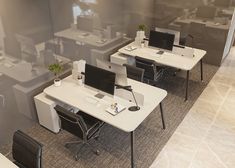 an office cubicle with two desks and one computer on the table, in front of a glass wall