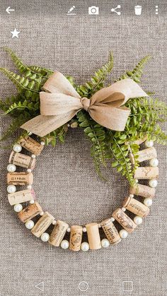 a wreath made out of wine corks and ferns with a bow on the front