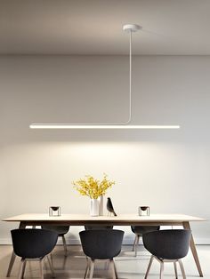 a dining room table with four chairs and a vase on the table in front of it