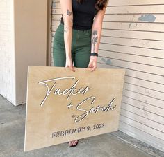 a woman holding up a wooden sign that says, trucker and sabk