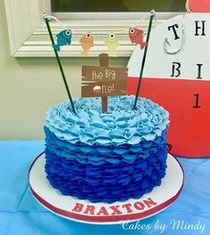 a cake with blue icing and some decorations on the top is sitting on a table