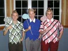 four people dressed up in costumes posing for a photo with one holding a fan and the other holding a pinwheel