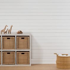 a toy giraffe is sitting on top of a dresser next to some baskets