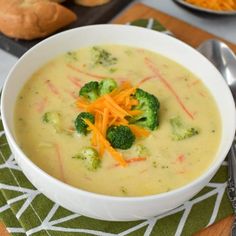 a white bowl filled with broccoli and carrots next to a slice of bread