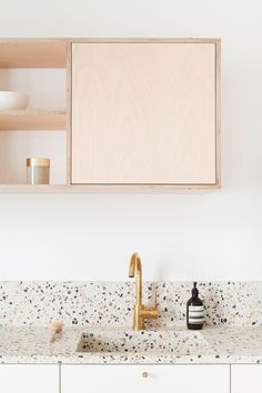 a bathroom sink with a wooden cabinet above it and an empty bottle on the counter