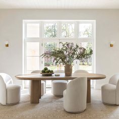 a dining room table with chairs and a potted plant in the middle on top