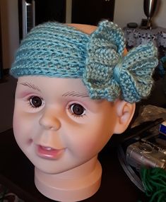 a doll head with a blue knitted bow on it's head and hair clip