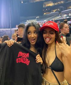 two women in bikinis holding up shirts and posing for the camera at a sporting event