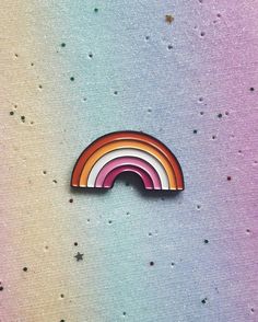 a rainbow pin sitting on top of a pink and blue background with lots of stars