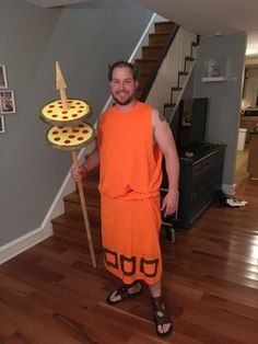 a man in an orange outfit holding a pizza on a stick