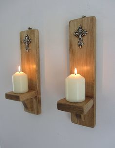 two wooden wall mounted candle holders with crosses on the front and one holding a lit candle